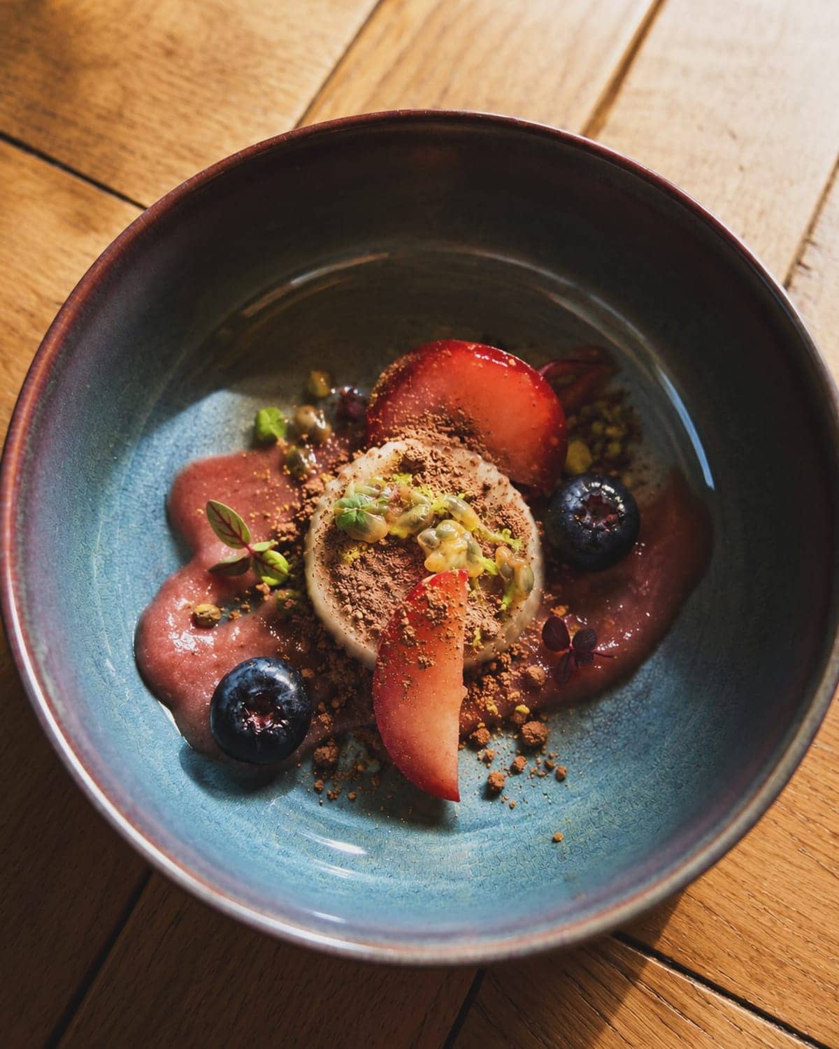 Japanese soufflé pancake with plum, blueberries and berry coulis in a blue bowl